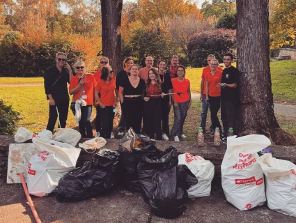 Groupe de collaborateurs posant devant les sacs de déchets collectés lors d’une action RSE dans un parc