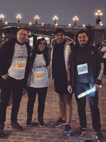 Quatre collaborateurs souriants participant à la Course des Lumières en tenue de sport et dossards