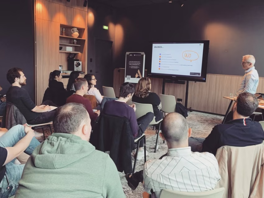 Collaborateurs assistant à une présentation animée par un intervenant dans une salle de réunion moderne