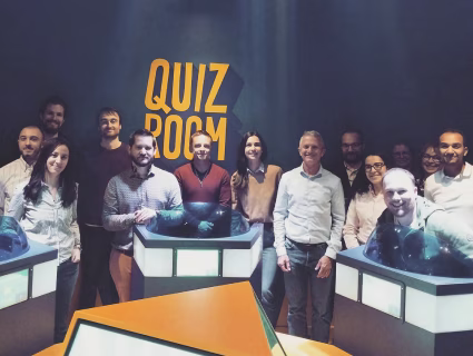 Équipe d’entreprise participant à une activité de quiz interactif dans une salle de jeu type “Quiz Room”