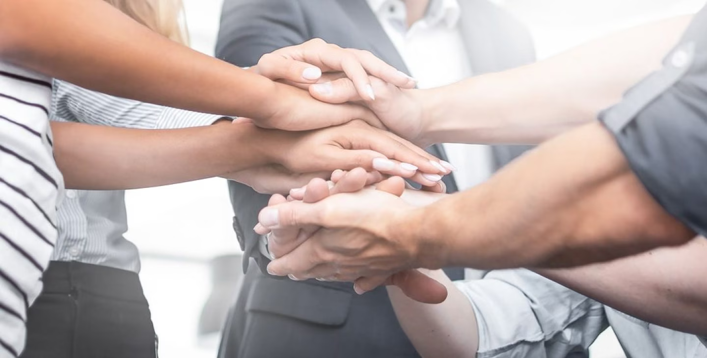 Gros plan sur plusieurs mains superposées en signe de collaboration et d’esprit d’équipe dans un environnement professionnel