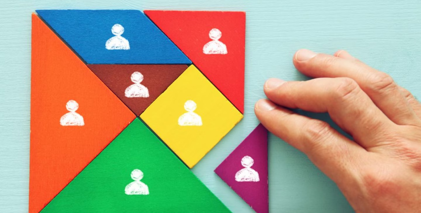 Main assemblant un puzzle coloré avec des icônes de personnes sur chaque pièce, symbolisant la diversité et la collaboration