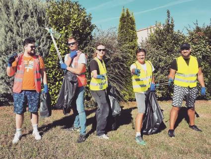 Groupe de collaborateurs en gilets de sécurité participant à une opération de ramassage de déchets en extérieur