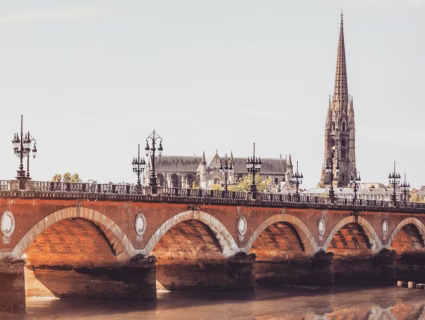 Vue du Pont de Pierre à Bordeaux enjambant la Garonne, avec la flèche Saint-Michel en arrière-plan