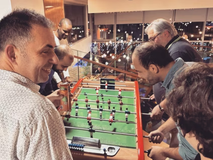 Groupe de collègues jouant au baby-foot dans un espace de détente lors d’un événement d’entreprise